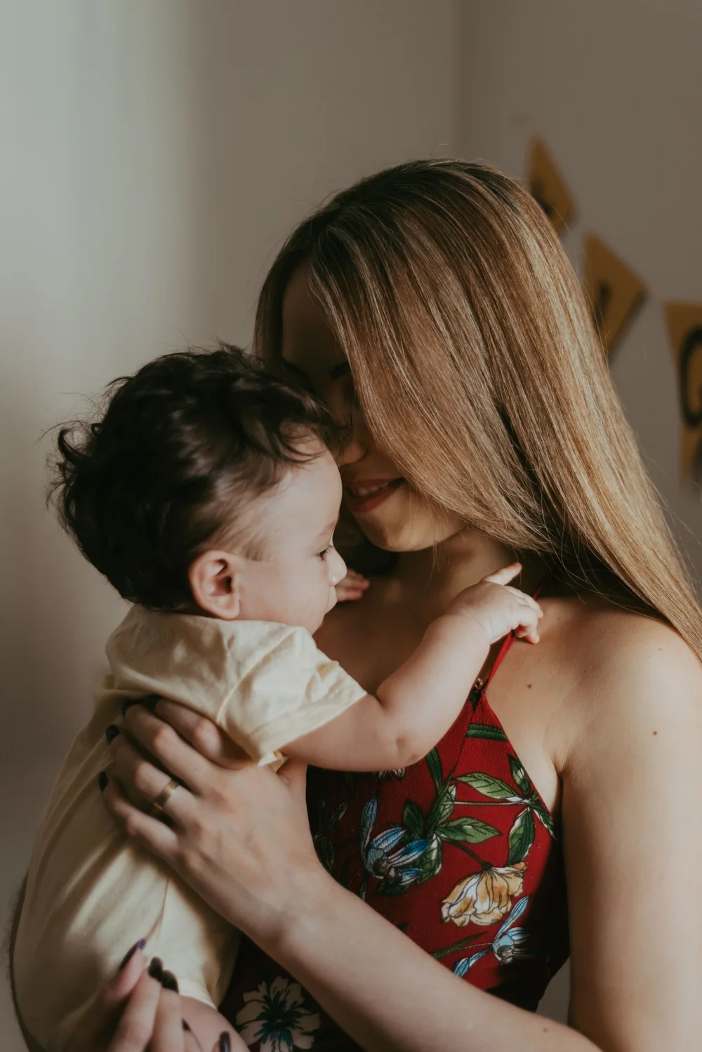A mother smiling at her baby held close in her arms